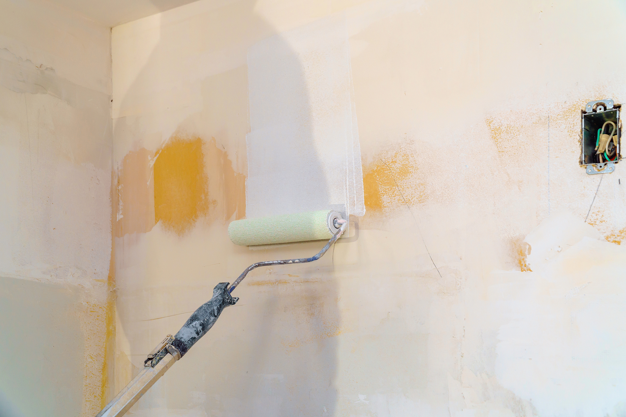 Painter priming water damaged walls after cleaning