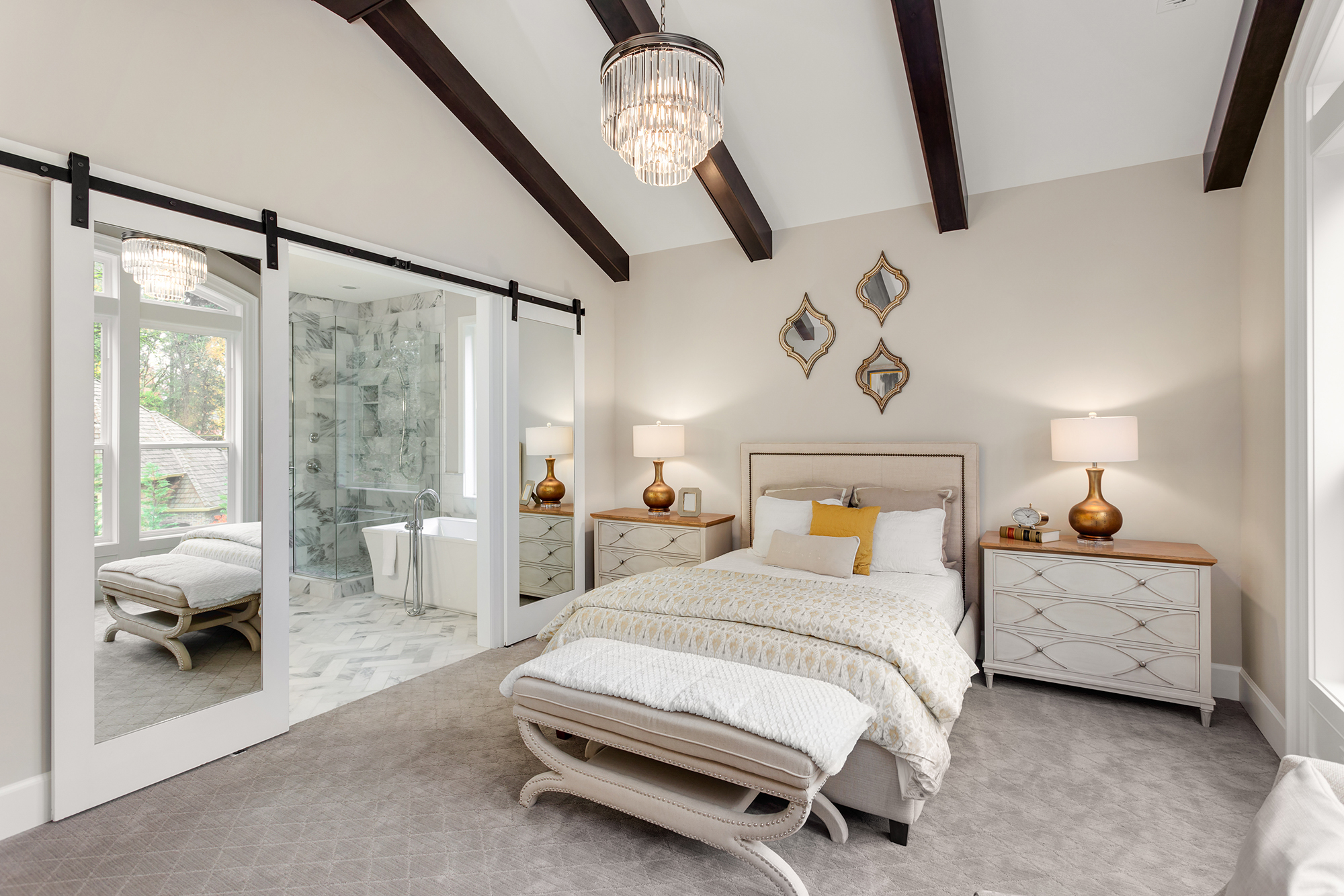 Beautiful bedroom with white painted walls and dark stained exposed beams and sliding barn door