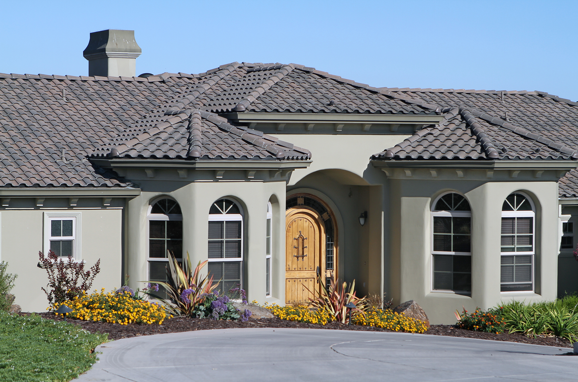 Close up of stucco house with gray painted exterior and finished wood front door